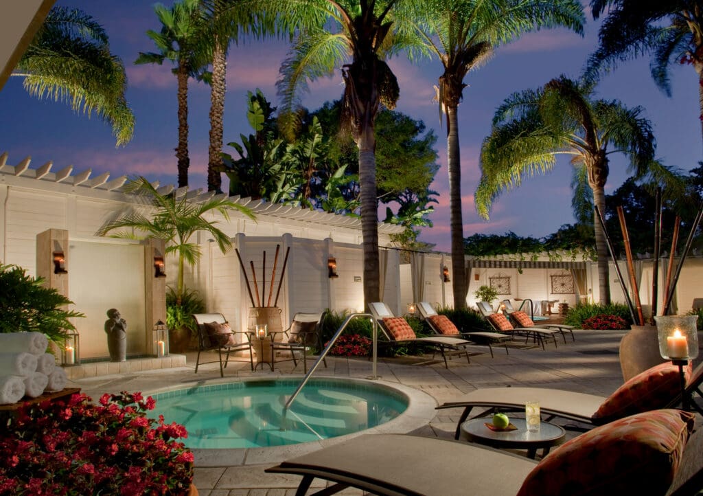 A hot spa, lounge chairs and palm trees at The Loews Coronado Bay Resort Sea Spa in the evening.