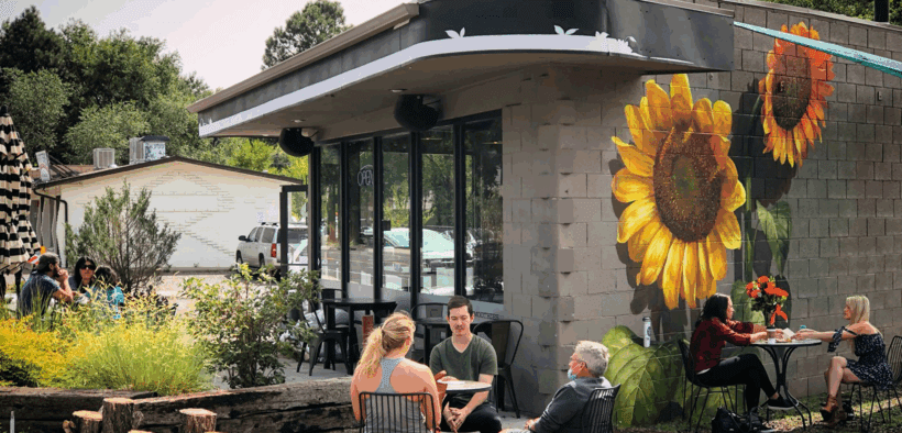 People sit outside of a Flagstaff business with giant painted sunflowers.