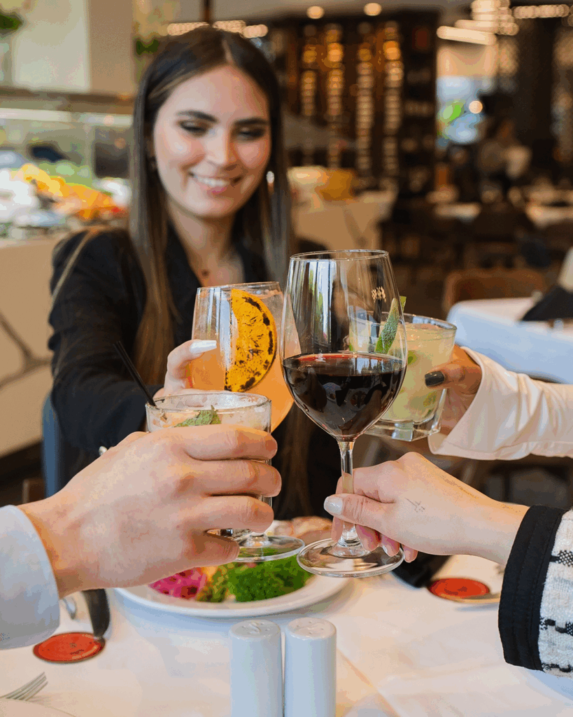 A woman cheers her cocktail glass with glasses of friends at Terra Gauch at Desert Ridge Marketplace.