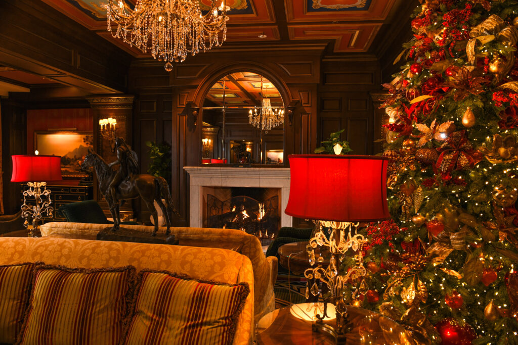 The lobby of the The Broadmoor in Colorado Springs with a comfy couch, fire in the fireplace, a Christmas tree and other holiday decor.