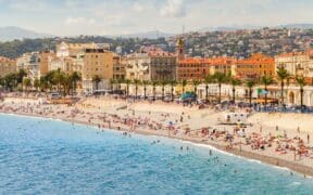 Coastal landscape with people resting on the beach along the Promenade des Anglais in Nice. French Riviera, France.