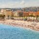 Coastal landscape with people resting on the beach along the Promenade des Anglais in Nice. French Riviera, France.