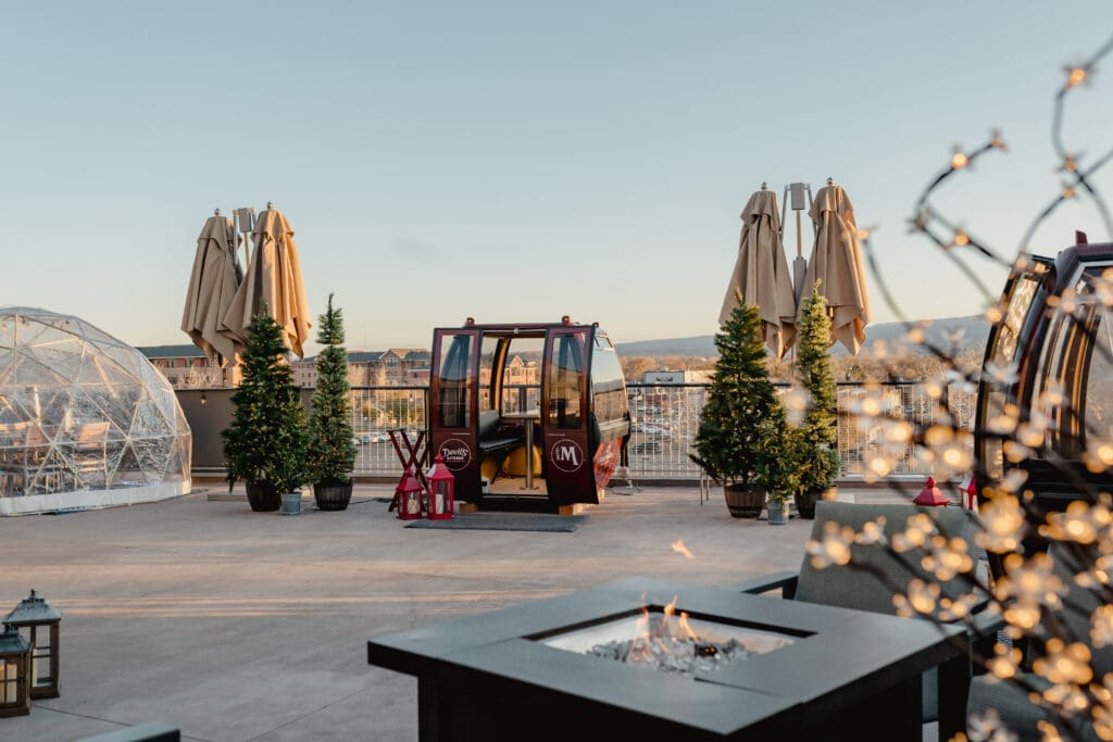 A gondola sitw between Christmas trees with a firepit in the foreground in Grand Junction, Colorado.
