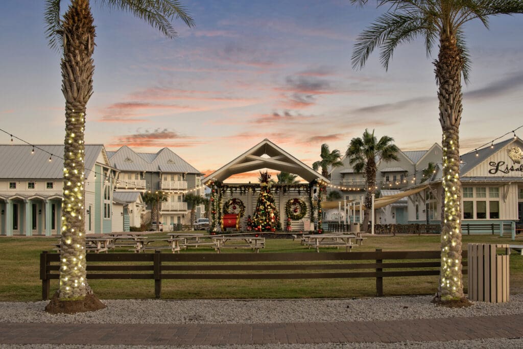 Tables with benches in a green area with a Christmas tree and wreaths near Cinnamon Shore rental properties in Port Aransas, Texas.