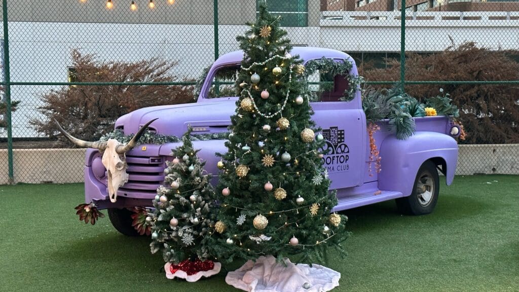 Two Chirstmas trees in front of a purple vintage truck at Holiday Happenings at The Worthington & Toro Toro in Fort Worth, Texas.