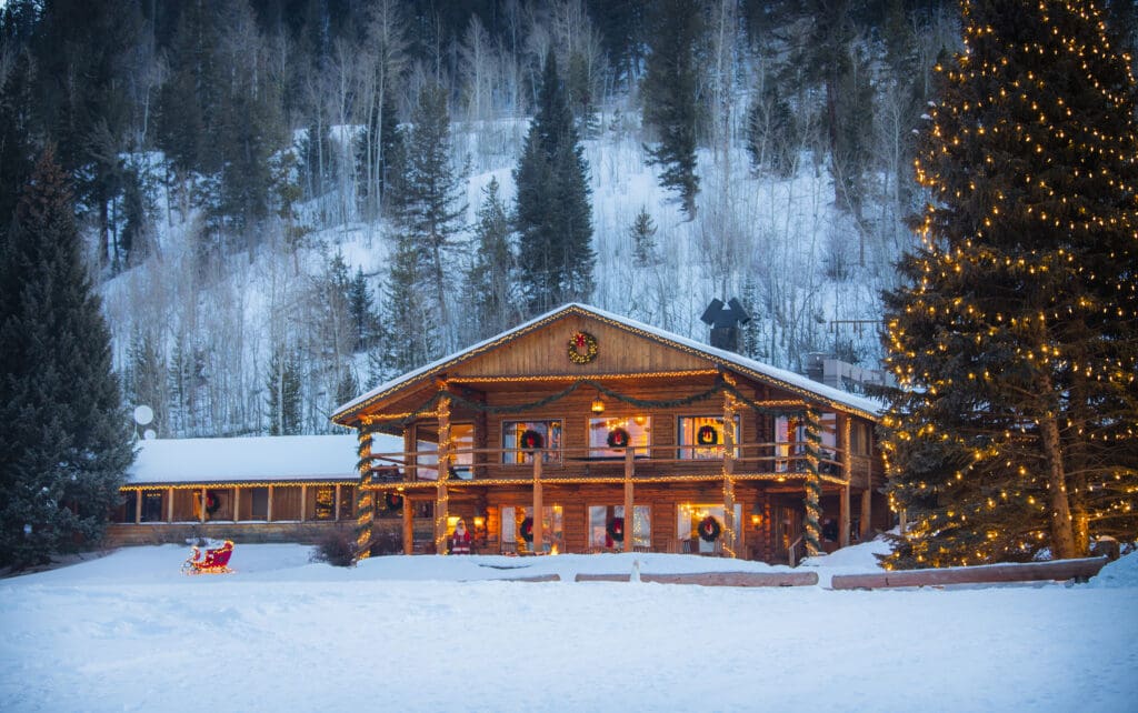 The C Lazy U Ranch in Granby, Colorado is decorated for the holidays with Christmas lights during a snowy evening. 