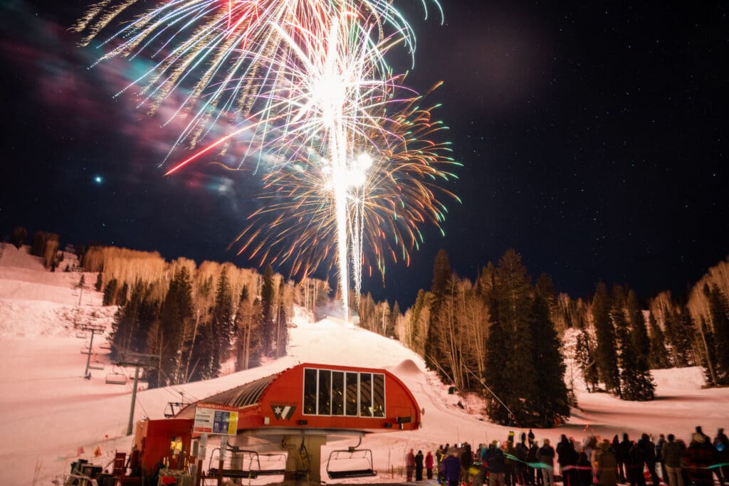 Fireworks explode above a lodge on the snow and tree covered mountain at Purgatory Resort in Durango, Colorado.