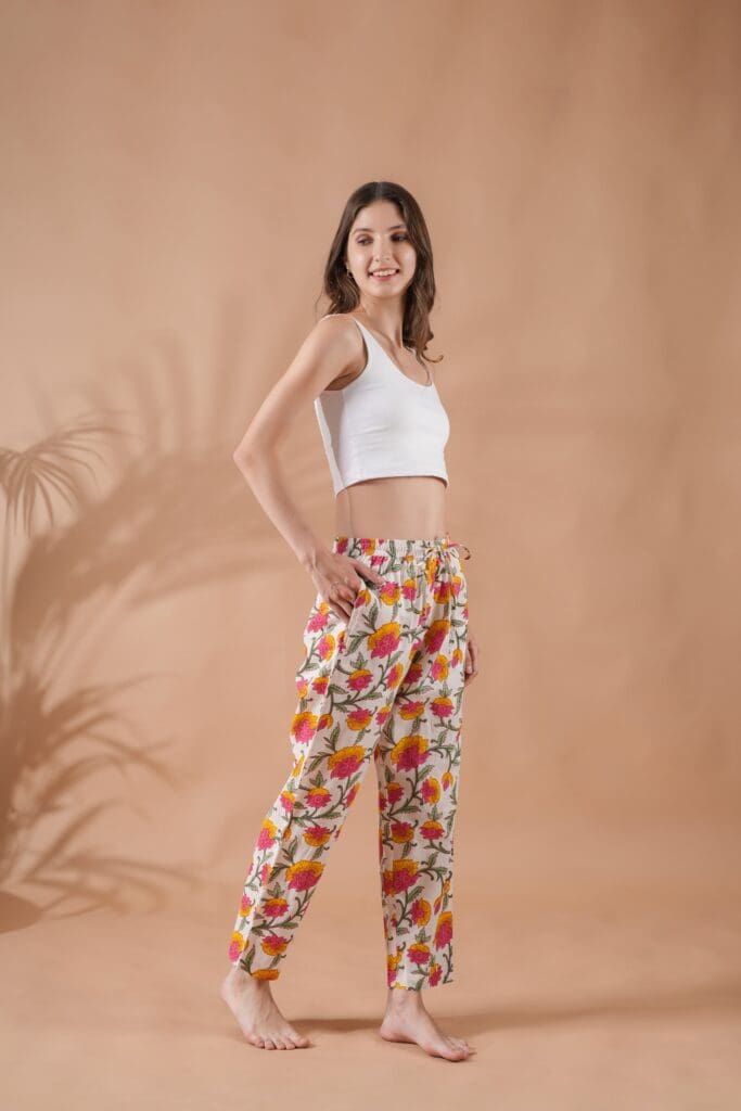 A woman wears a white, cropped tank with Floral Whispers print Zillajee cotton pajama bottoms.