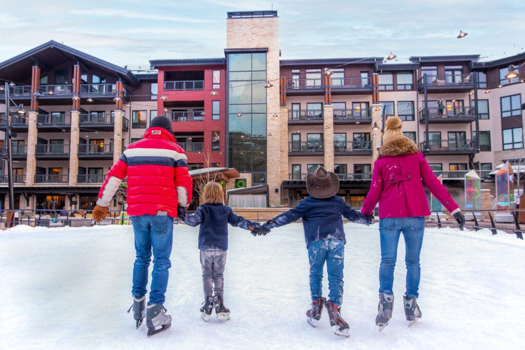 A family of four ice skates on a rink at  Snowmass Village in Colorado.
