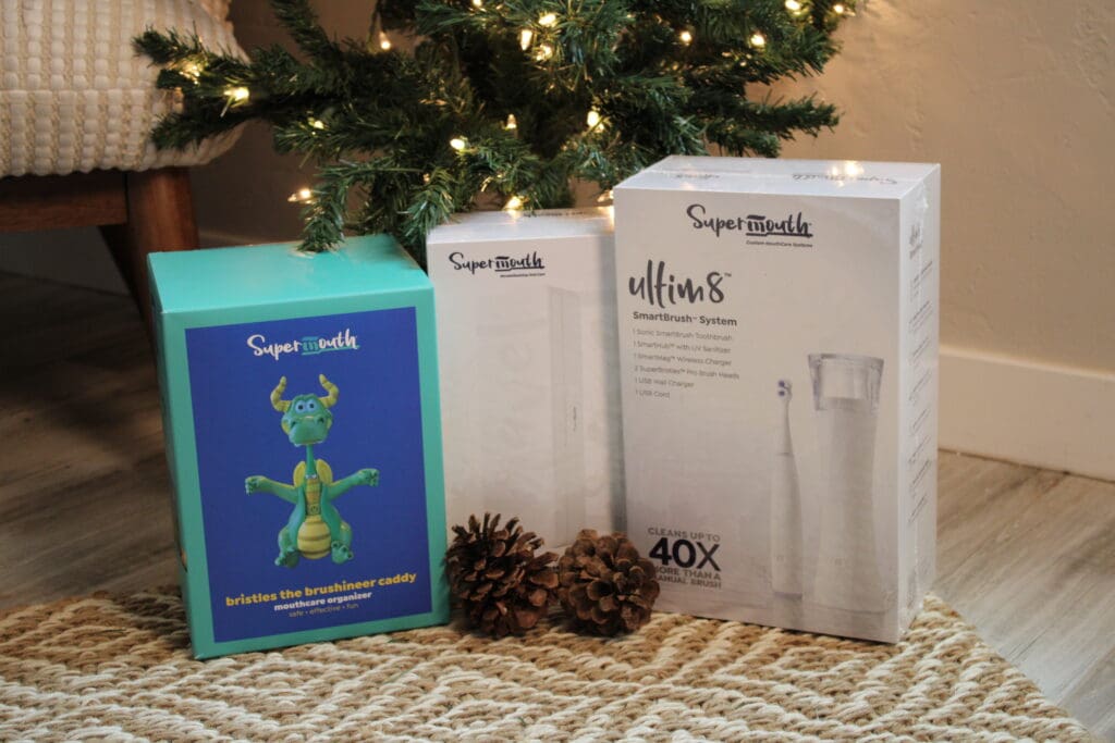 Three gift sets from SuperMouth under a Christmas tree. 