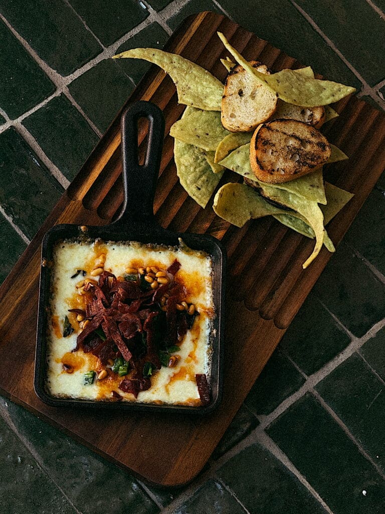A tiny ceramican skillet with warm dip and a neat pile of chips ans toasted bread for dipping at Estelle restaurant in Scottsdale.