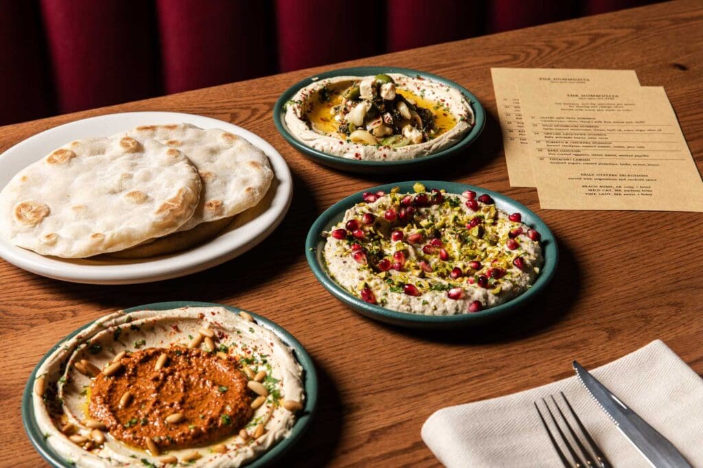 Plates of naan and hummus on a table next to place settings and menus at Pinyon in Scottsdale.