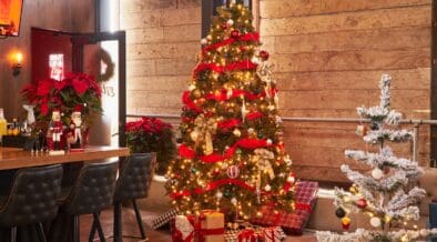 Two decorated Christmas trees with presents underneath at Culinary Drop Out in Phoenix.