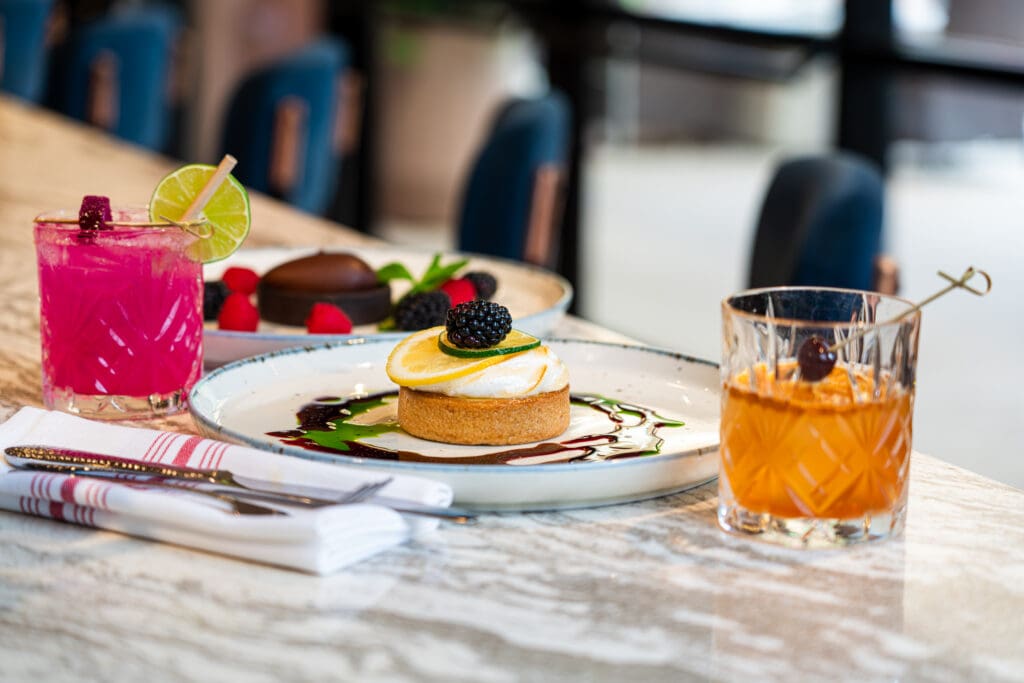 Two cocktails next to a napkin place setting and two dessert plates at  ShadowRock Tap + Table, Hilton Resort at Bell Rock.