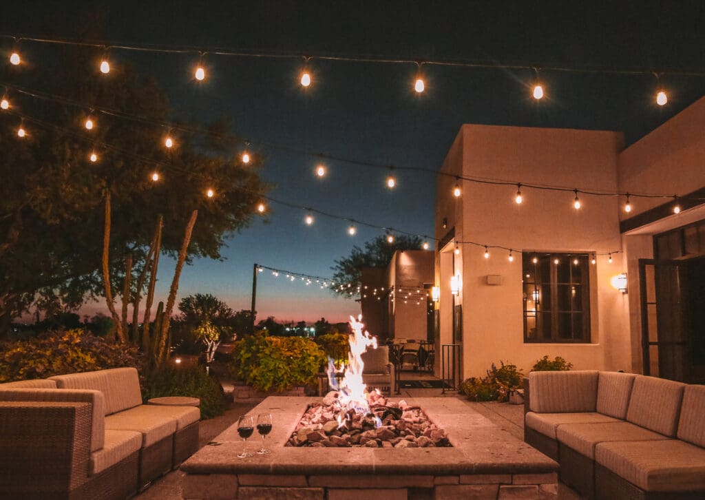 Lights strung over a firepit and couches on the outdoor porch of a JW Marriott Scottsdale Camelback Inn Resort & Spa.