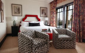 New Braunfels historic landmark, The Faust Hotel's renovated guestroom with a king bed and two stylish chairs.