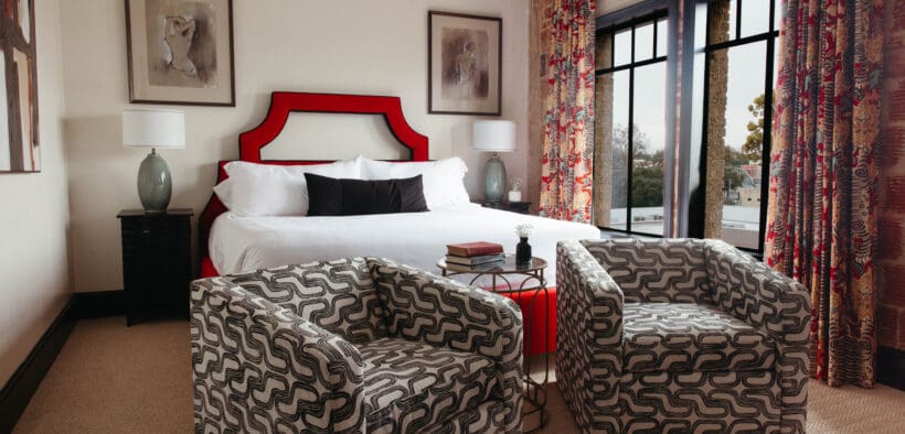 New Braunfels historic landmark, The Faust Hotel's renovated guestroom with a king bed and two stylish chairs.