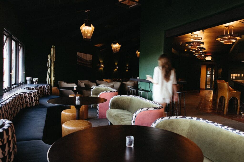 A woman walks by tables, booths and couches at Lady Duff's Lounge at Hotel Glorieta in Santa Fe, New Mexico.