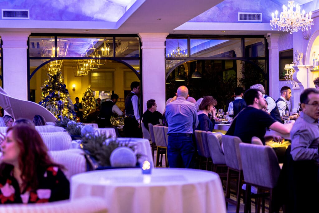People fill the dining area and bar at The Italiano during the holidays with Christmas trees and decors throughout.