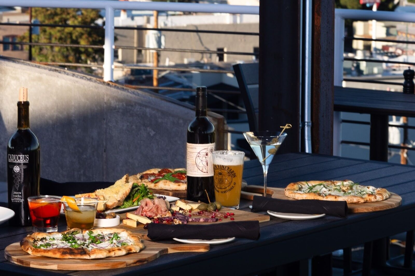 An outdoor tale with beer, wine bottles, cocktails and charcuterie at Merkin Vineyards Hilltop Winery & Trattoria. 