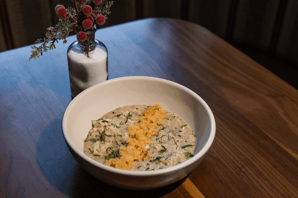 A bowl of Blue Crab Cacio e Pepe Risotto and holly berry decoration at North Italia in Arizona. 