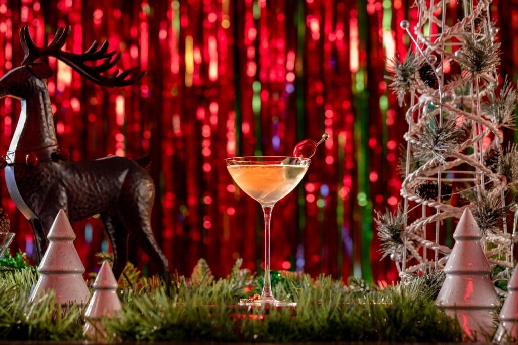 A cocktail glass with garnish surrounded by holiday decor and streamers at Omni Scottsdale Resort & Spa at Montelucia.
