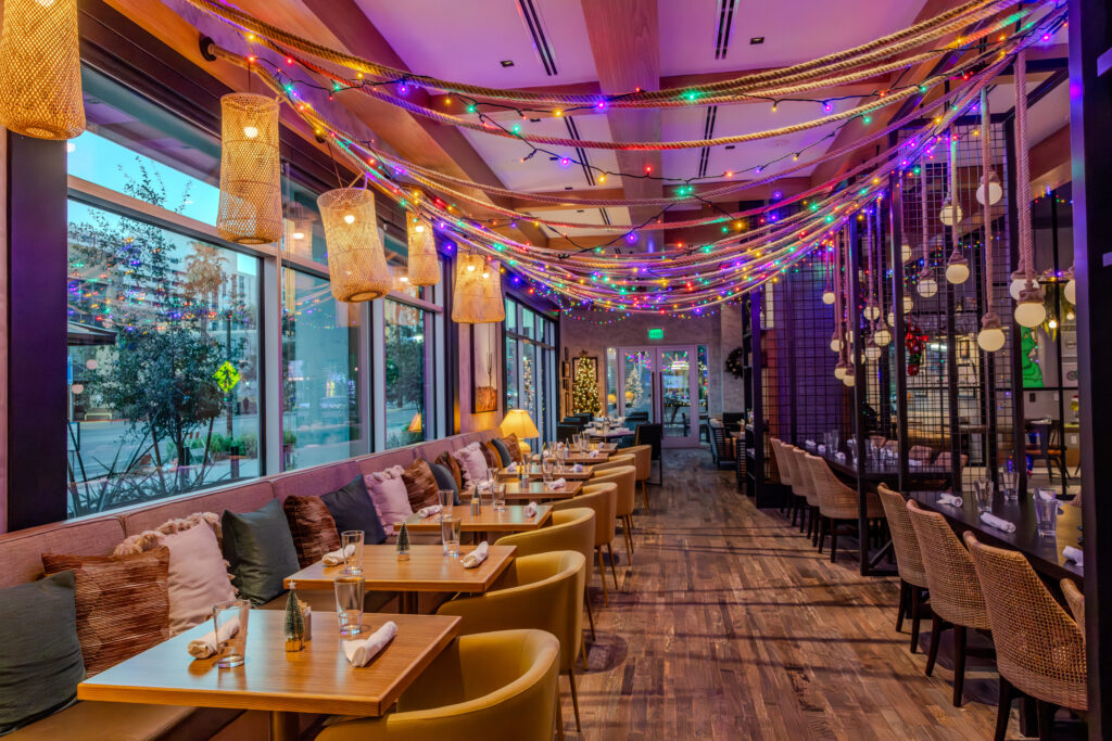 Lucero at Omni Tempe Hotel at ASU with booth seating and decorative pillows, tables and string Christmas lights and decor.