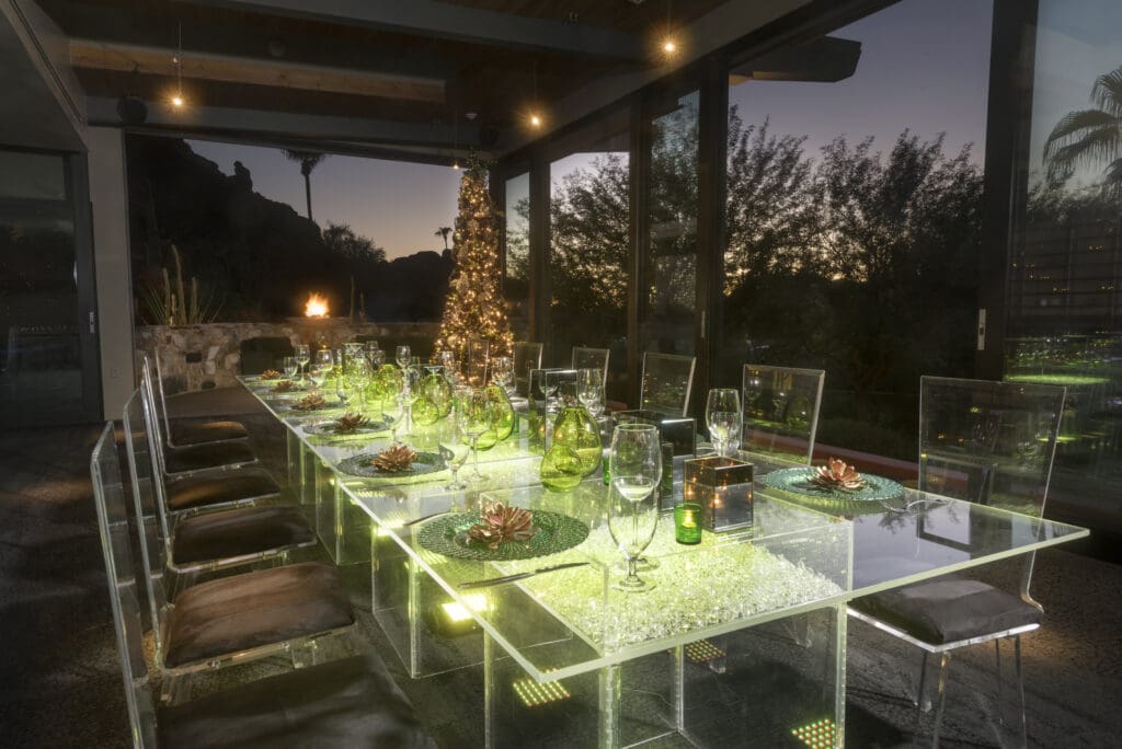 An upscale glass table and chairs set for New Year's Eve with a Christmas tree in the background at Sanctuary Camelback Mountain Resort & Spa.