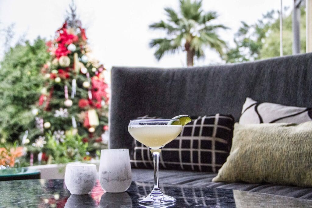 A martini glass next to candles with comfy pillows , a couch and lit up Christmas tree at Sanctuary Camelback Mountain Resort & Spa.