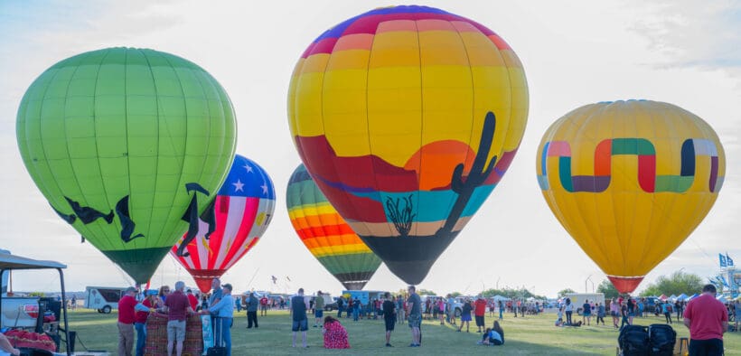 Five hot air balloons with varying designs, mostly with desert depictions at Wild Horse Pass for the Arizona Balloon Classic.
