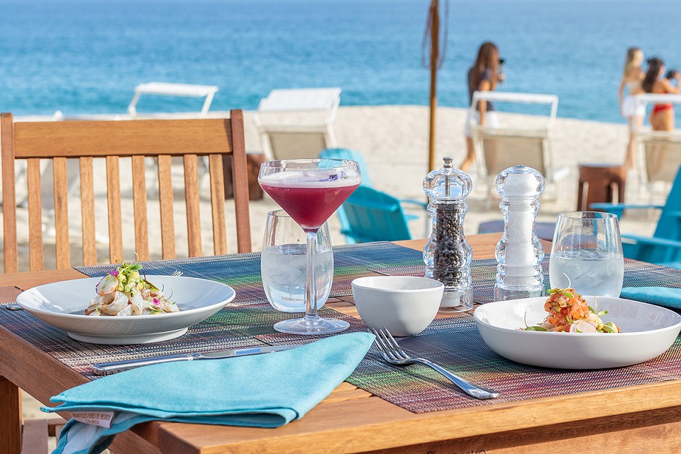 Table set with lunch bites and coktails from the on-site food truck at Garza Blanca Resort & Spa Los Cabos as beachside dining.
