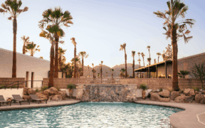 The pool at Kimpton Miralina Resort & Villas Paradise Valley surrounded by rocks and palm tree landscaping.
