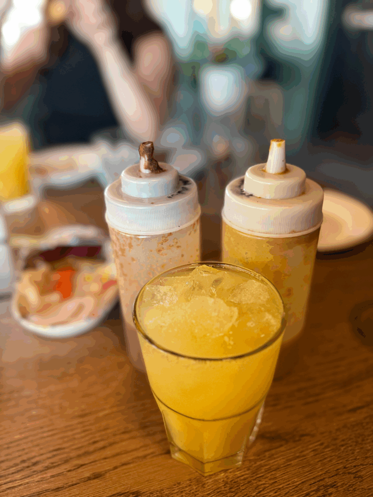 Two hot sauce containers and a chai orange beverage at Tandoori Tacos at Maven District in Salt Lake City.