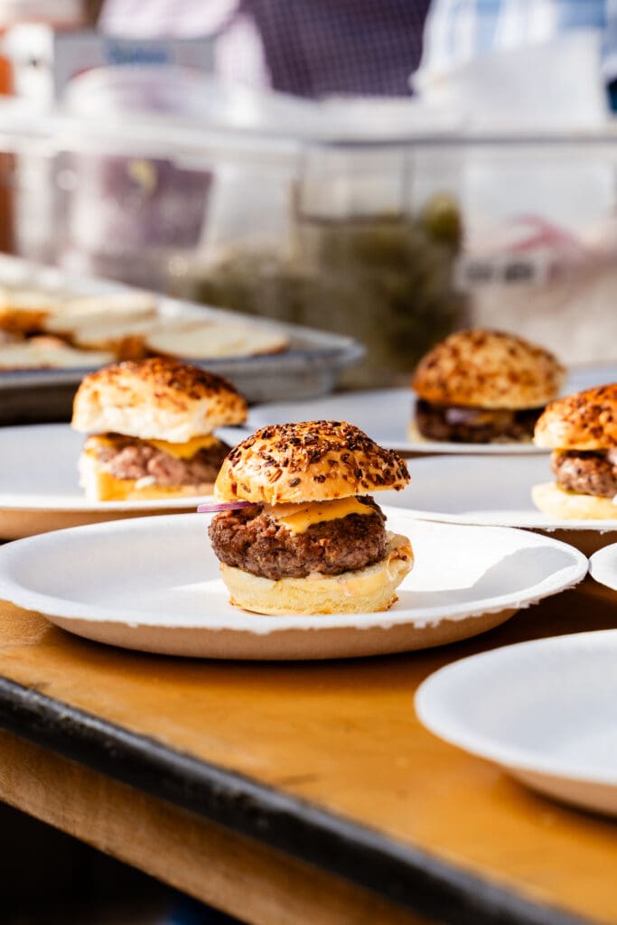 Mini cheeseburgers with onion and artisan buns on paper plates at Taste of AZ in Scottsdale,